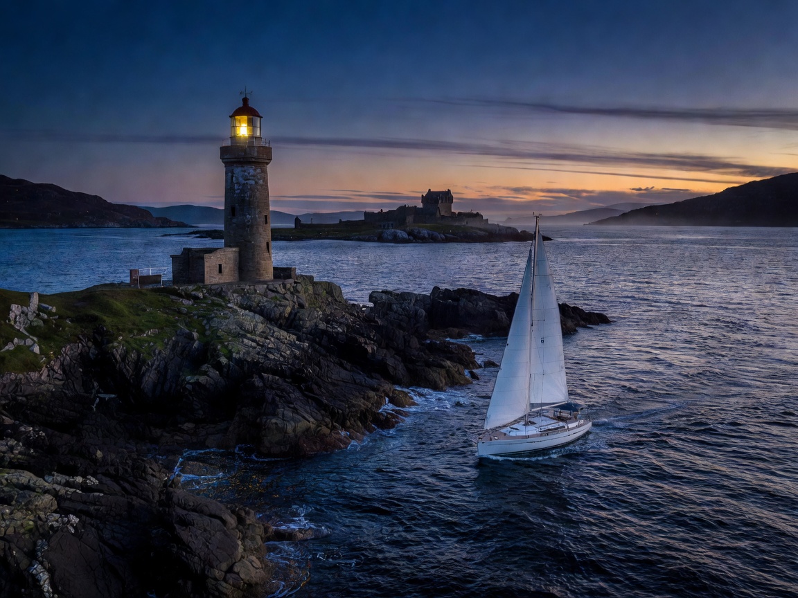 A lighthouse on a dark rocky point in the Sound of Mull at dusk, with a yacht passing under sail and Duart Castle in the distance